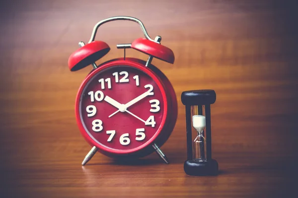 clock and mini sand clock on wooden background, copy spae.