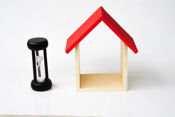  sand clock and miniature house on a white background, copy spae.