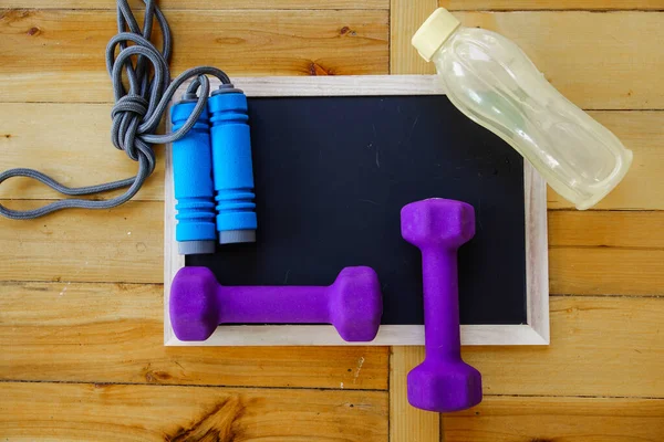 Spor, spor konsepti. Koşan spor ayakkabılar, su şişesi, kulaklıklar, dambıllar, akıllı telefon, ahşap arka planda fotokopi alanı