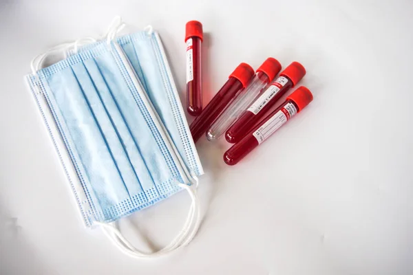 Kelantan, Maaysia - 13.02.2021: Mavi arka planda kan örneği ve yüz maskesi olan test tüpü.