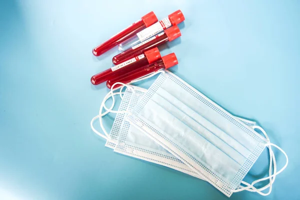 Kelantan, Maaysia - 13.02.2021: Mavi arka planda kan örneği ve yüz maskesi olan test tüpü.