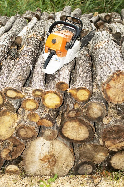 Gasoline powered  chainsaw on pile of cut wood — Stock Photo, Image