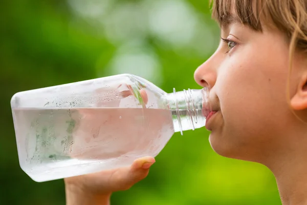 Girl dricka rent kranvatten från genomskinligt glasflaska — Stockfoto