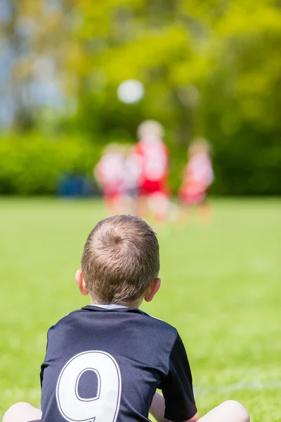 Jovem assistindo um jogo de futebol infantil — Fotografia de Stock