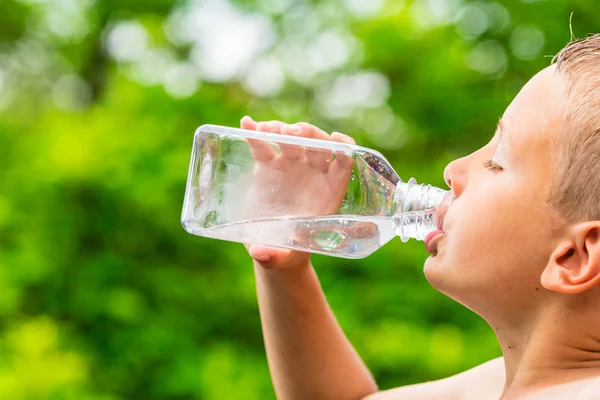 Хлопчик п'є чисту воду з прозорої пластикової пляшки — стокове фото
