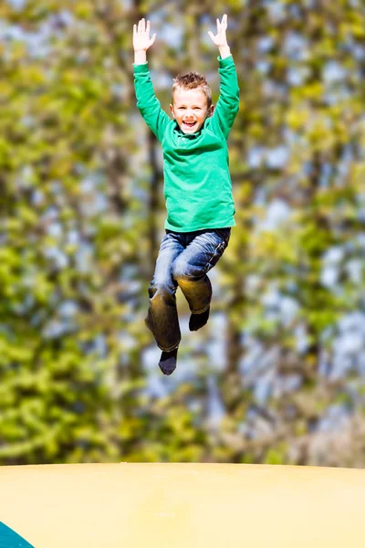 Lycklig pojke hoppar på studsmatta — Stockfoto