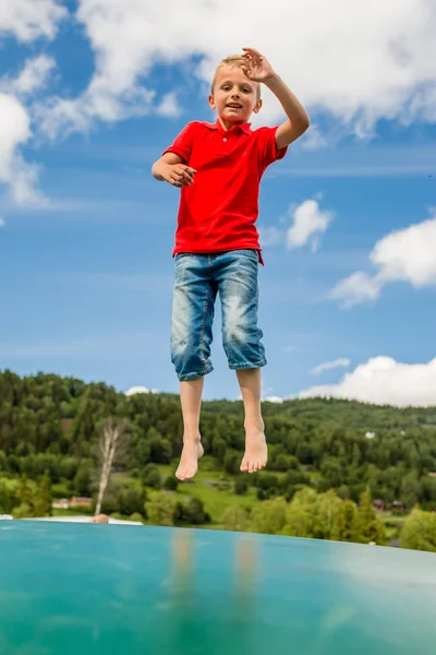 Молодий хлопчик стрибає на підстрибуючій подушці — стокове фото
