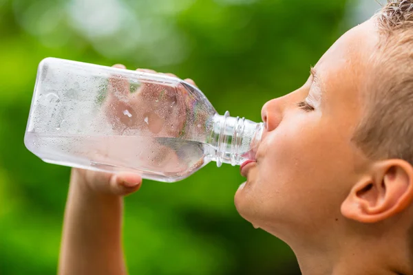 Boy drinking clean tap water from transparent plastic bottle — Stock Photo, Image