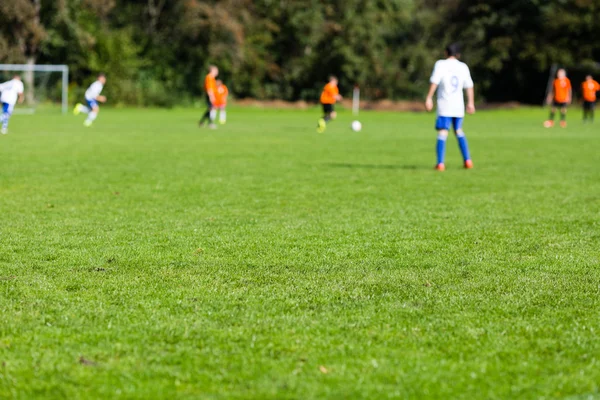 Blurred soccer players on green pitch — Stock Photo, Image