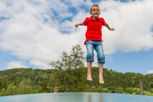 Ung pojke hoppar på studsmatta — Stockfoto