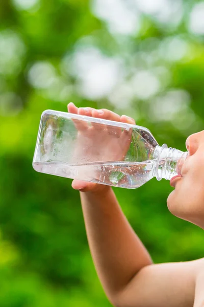 Criança bebendo água da torneira limpa de garrafa de plástico transparente — Fotografia de Stock