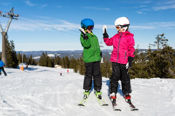 Dos niños esquiadores haciendo cinco en la pista de esquí —  Fotos de Stock