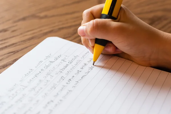 Niño escribiendo a mano en el bloc de notas — Foto de Stock