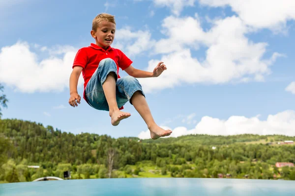 Young boy jumping on bouncing pillow — Stock Photo, Image