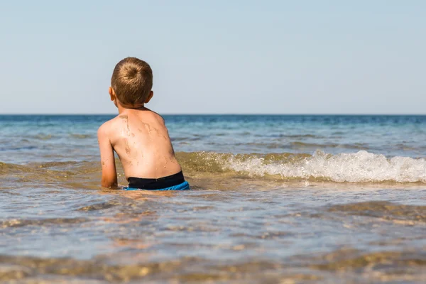 Junge spielt im Ozean — Stockfoto