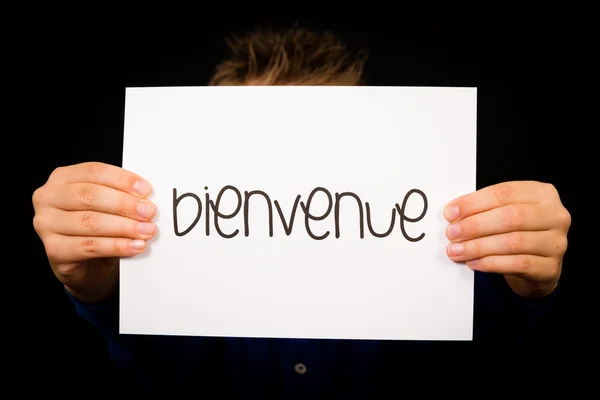 Kind hält Schild mit französischem Wort bienvenue - willkommen — Stockfoto