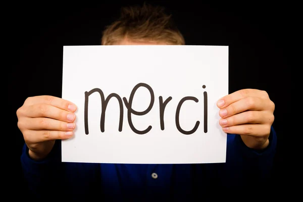 Kind hält Schild mit französischem Wort merci - danke — Stockfoto