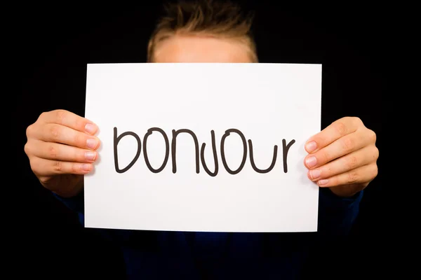 Kind hält Schild mit französischem Wort bonjour - hallo — Stockfoto