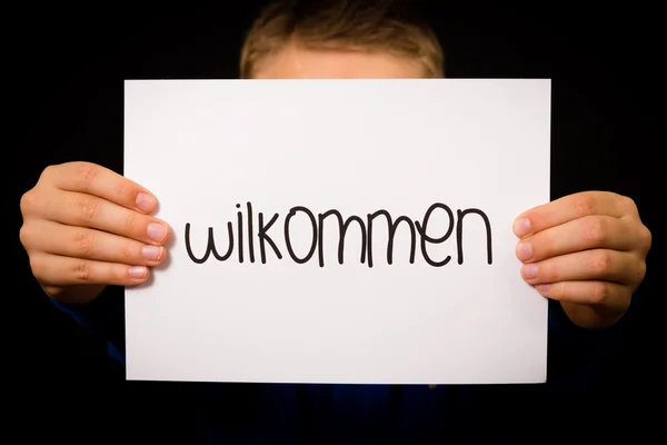 孩子举牌子与德语单词 Wilkommen-欢迎 — 图库照片