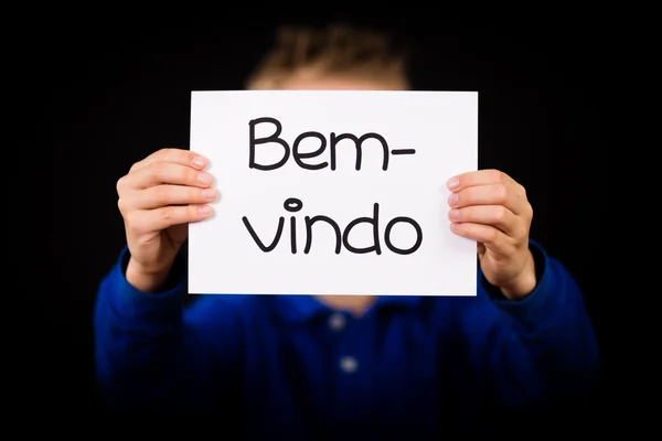 Kind hält Schild mit portugiesischem Wort bem-vindo - willkommen — Stockfoto