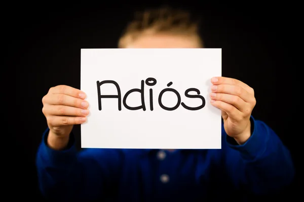 Kind hält Schild mit spanischem Wort adios - auf Wiedersehen — Stockfoto
