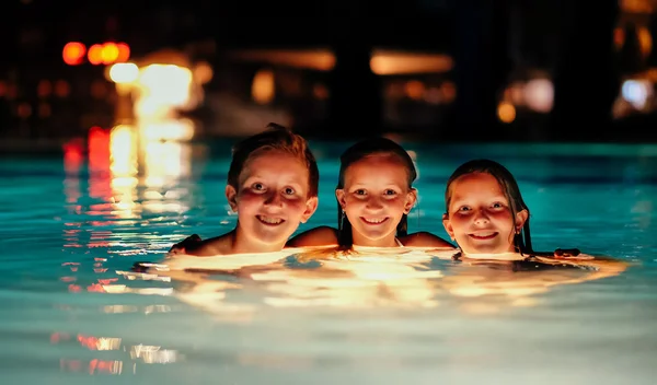 Three kids in illuminated pool — Stock Photo, Image