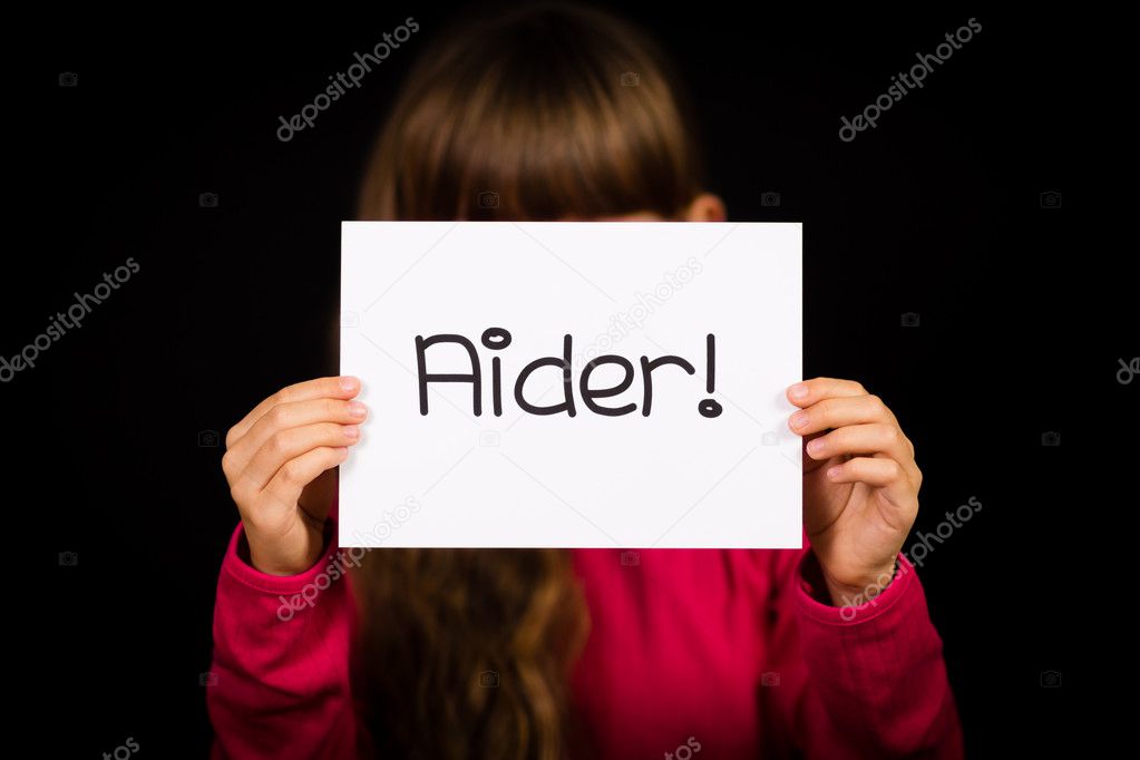 Child holding sign with French word Aider - Help