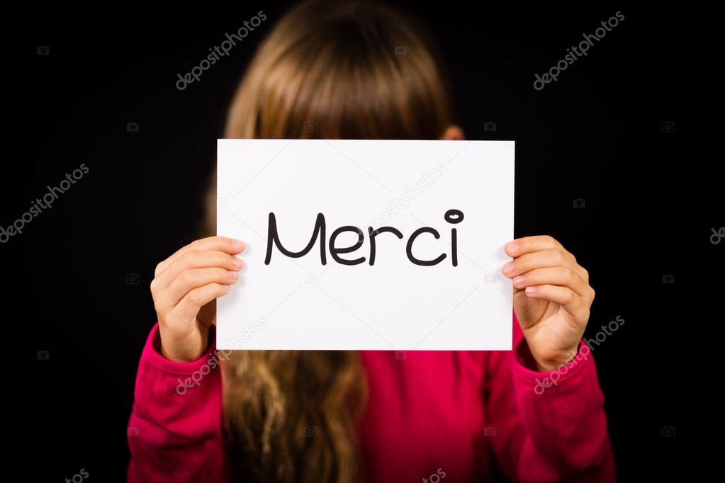 Child holding sign with French word Merci - Thank You