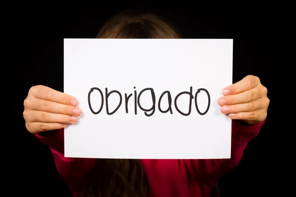 Ребенок держит табличку с португальским словом Obrigado - Спасибо — стоковое фото
