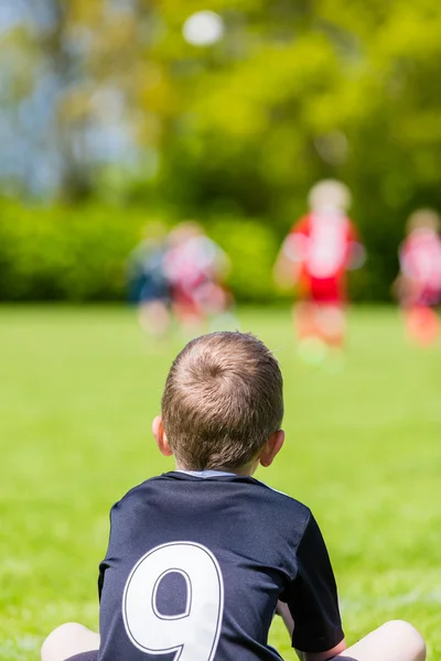 Jovem assistindo um jogo de futebol infantil — Fotografia de Stock