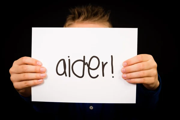 Child holding sign with French word Aider - Help — Stock Photo, Image