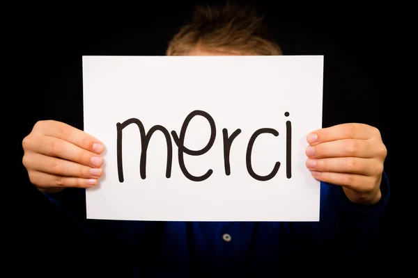 Kind hält Schild mit französischem Wort merci - danke — Stockfoto