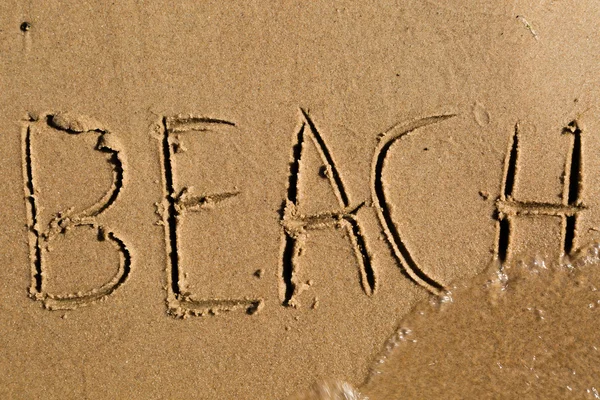 Het strand van de woord geschreven in het zand — Stockfoto