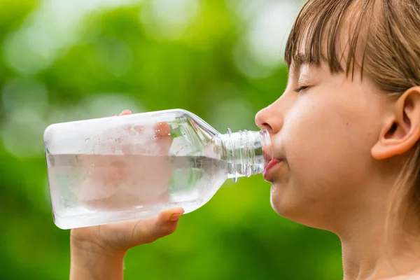 Girl dricka rent kranvatten från genomskinligt glasflaska — Stockfoto