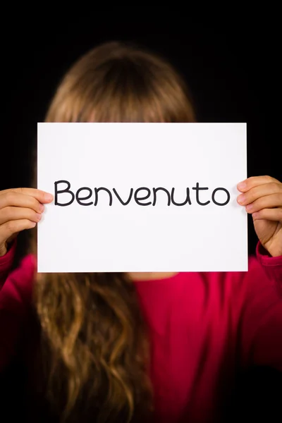 Kind hält Schild mit italienischem Wort benvenuto - willkommen — Stockfoto