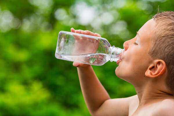 Boy drinking clean tap water from transparent plastic bottle