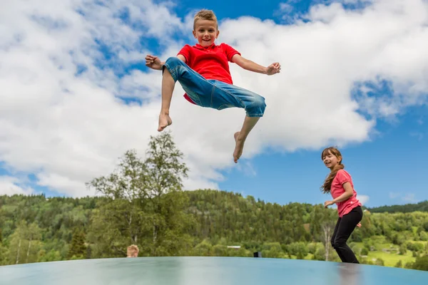 Dzieci podskakują w górę iw dół na trampolinie — Zdjęcie stockowe