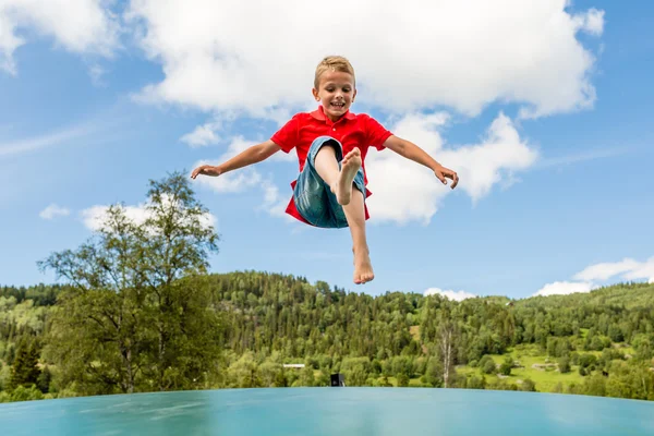 Young boy jumping on bouncing pillow — Stock Photo, Image