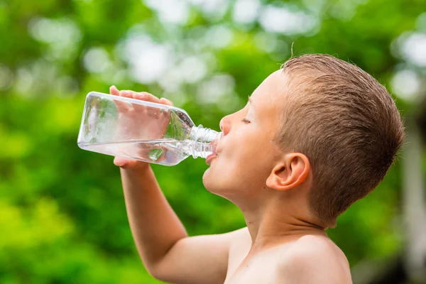 Мальчик пьет чистую воду из прозрачной пластиковой бутылки — стоковое фото