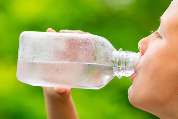 Child drinking clean tap water from transparent plastic bottle — Stock Photo, Image