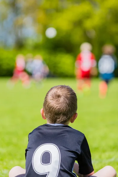 Jovem assistindo um jogo de futebol infantil — Fotografia de Stock