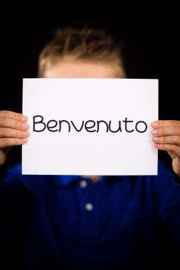 İtalyanca kelime Benvenuto - Hoşgeldiniz işaretiyle tutan çocuk
