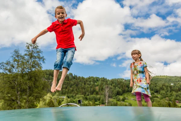 Dzieci podskakują w górę iw dół na trampolinie — Zdjęcie stockowe