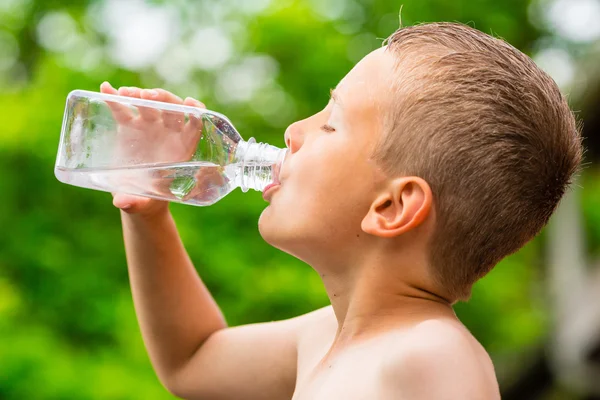 Menino bebendo água da torneira limpa de garrafa de plástico transparente — Fotografia de Stock