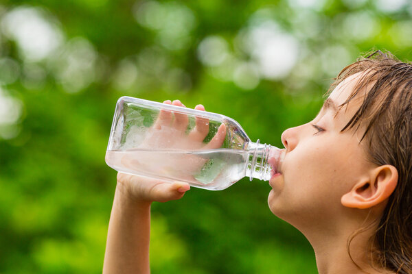 Girl drinking clean tap water from transparent plastic bottle