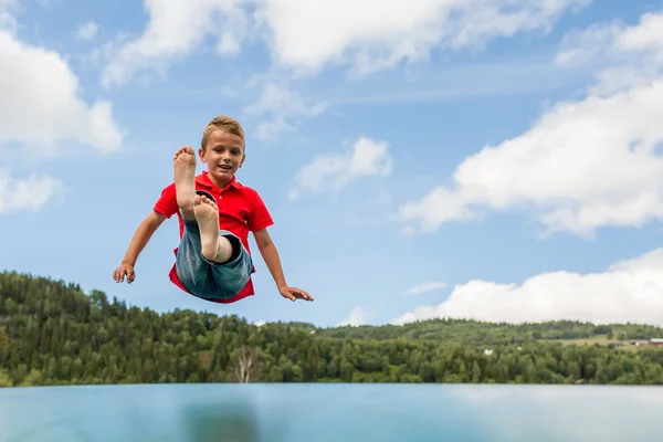 Young boy jumping on bouncing pillow — Stock Photo, Image