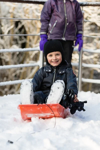 Bambino che gioca con la slitta nella neve invernale — Foto Stock