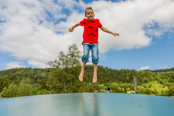 Young boy jumping on bouncing pillow — Stock Photo, Image