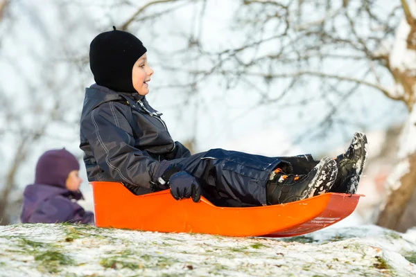 Boy sitting in sledge on sunny winter day — Stock Photo, Image