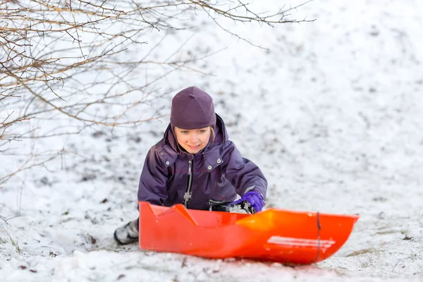 Дівчина грає з санчатами в зимовий сніг — стокове фото